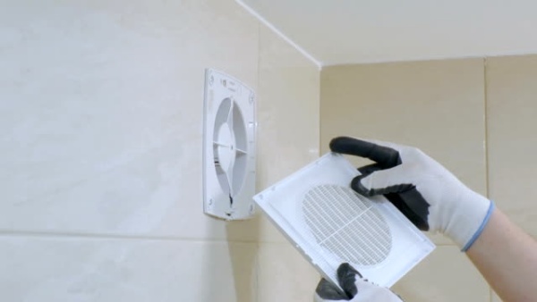 Workman is fixing the exhaust fan on the wall.